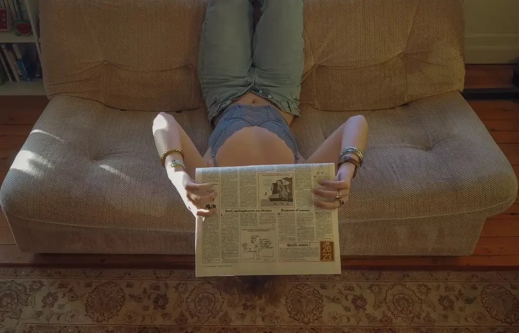 Femme lisant dans un canapé en ambiance boudoir, lumière douce et atmosphère intime.